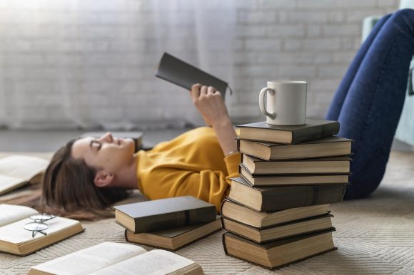 Donna che legge libri sdraiata a terra