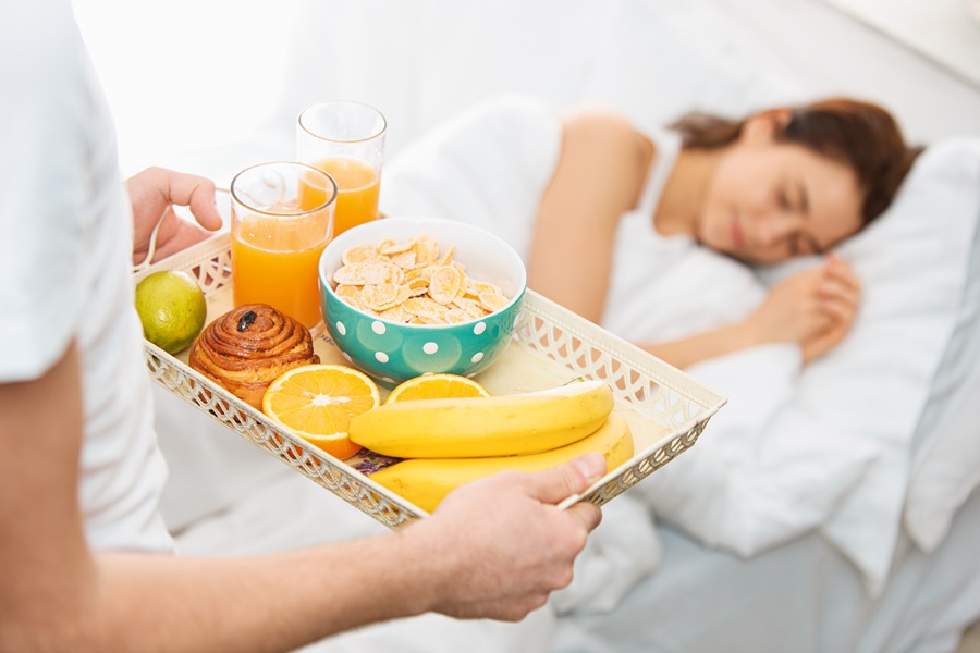 uomo che porta la colazione a letto alla propria moglie